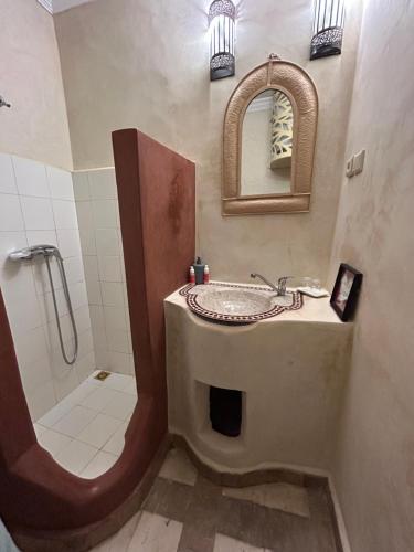 a bathroom with a sink and a shower with a mirror at Riad N10 in Marrakech