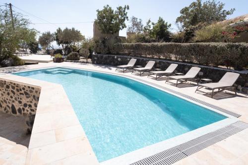 a swimming pool with lounge chairs next to a villa at Mantilida Villa in Emporio Santorini