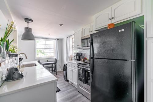 a kitchen with a black refrigerator and white cabinets at Short North Convention Private Parking Pets! in Columbus