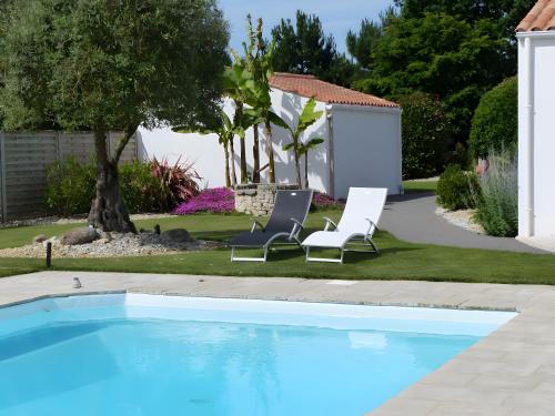 two chairs sitting next to a swimming pool at Le Clos De La Combe in Saint-Jean-dʼOrbetiers