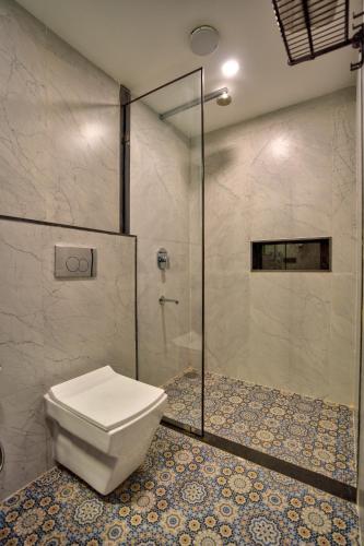 a bathroom with a toilet and a glass shower at Hotel Dimaru Boutique in Calangute