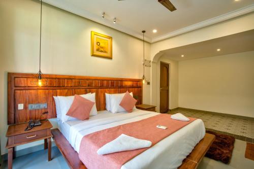 a bedroom with a large bed with a wooden headboard at Hotel Dimaru Boutique in Calangute