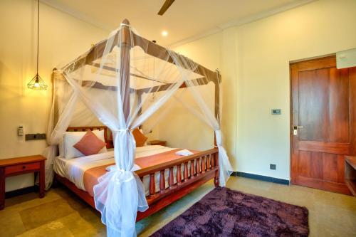 a bedroom with a bed with a canopy at Hotel Dimaru Boutique in Calangute