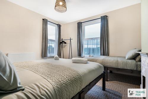 a bedroom with two beds and two windows at Sophie's House in Nottingham