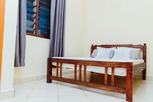a wooden bed with white pillows on it in a room at Frank's Homes in Kwale