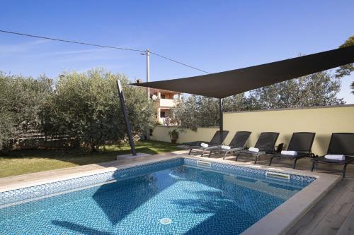 a swimming pool with chairs next to a house at Ferienhaus Captains in Vintijan