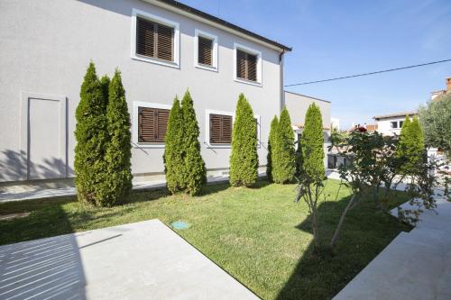 a row of trees in front of a white house at Ferienhaus Captains in Vintijan