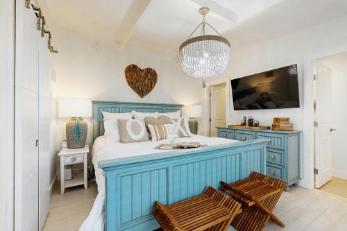 a bedroom with a blue bed with two chairs at Carpe Diem - Seas The Day in Key Colony Beach