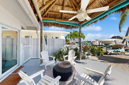 a porch with white chairs and a ceiling fan at Carpe Diem - Seas The Day in Key Colony Beach
