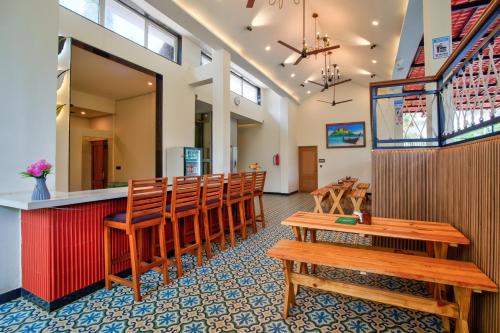 a restaurant with a row of wooden chairs and a bar at Hotel Dimaru Boutique in Calangute