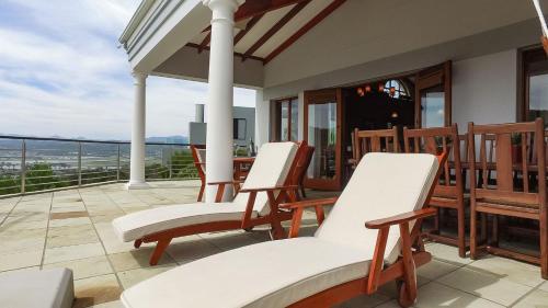 a porch with white chairs and a view of the ocean at Knysna Pearl View Guest House in Knysna