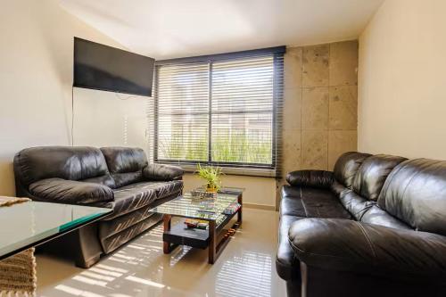 a living room with a leather couch and a table at Shinyado CDMX in Mexico City