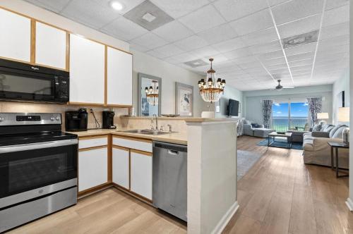 a kitchen with white cabinets and a living room at Sans Souci Unit 204 in Villa Sabine