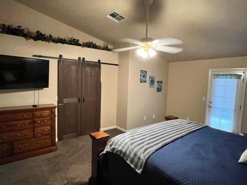 a bedroom with a bed with a ceiling fan and a tv at Mesquite paradise in Mesquite