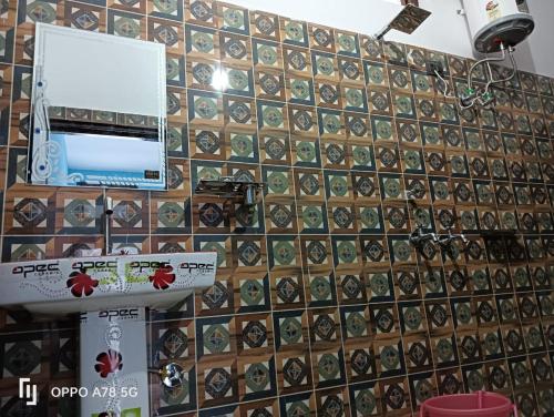 a bathroom with a tiled wall with a laptop on it at Panchkedar resort in Sonprayag