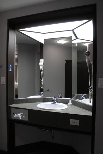 a bathroom with a sink and a large mirror at Travelodge by Wyndham Trois-Rivieres in Trois-Rivières