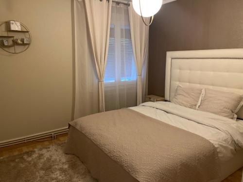 ein Schlafzimmer mit einem weißen Bett und einem Fenster in der Unterkunft Maison Chic à 10min du circuit des 24H in Allonnes