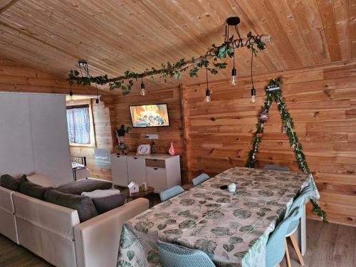 a dining room with a table and a couch at Chalet près du lac in Les Mazures