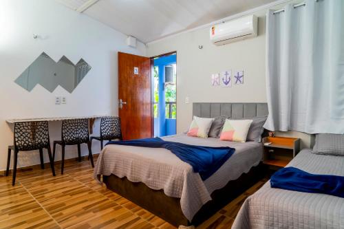 a bedroom with two beds and a table and chairs at Vila Davi Jeri - Flats e Casa in Jericoacoara