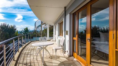 a patio with a table and chairs on a balcony at Knysna Pearl View Guest House in Knysna