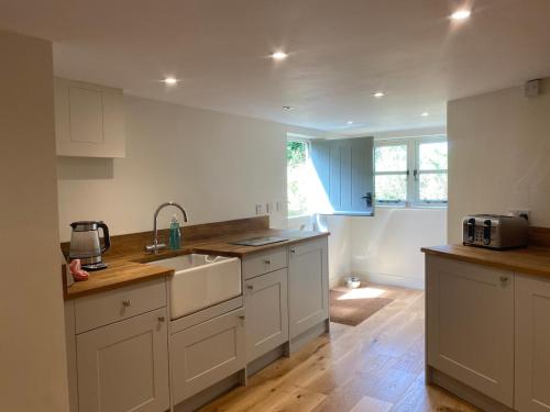 a kitchen with white cabinets and a sink at Boutique 2 bedroom cottage - North Norfolk coast in Hindringham