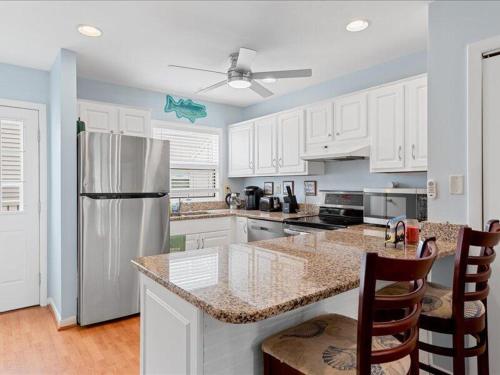 a kitchen with white cabinets and a stainless steel refrigerator at Seabreeze village 5 in Dewey Beach