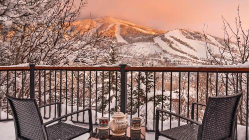 a table and chairs on a balcony with snow covered mountains at Glacier Lodge - East in Steamboat Springs