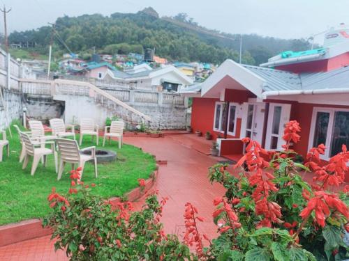 a patio of a house with white chairs and red flowers at Mountain View Private Villa in Ooty