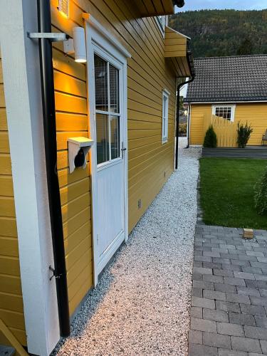 a yellow house with a door and a pathway at Sandvik Garasjeloft in Vossevangen