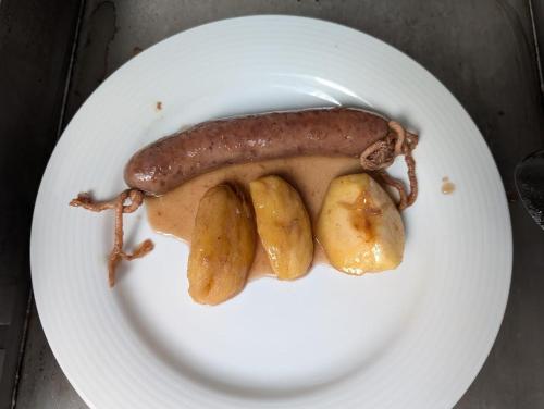 a sausage and potatoes on a white plate at 1703 CHAMBRE ET TABLE D'HOTES in Angoustrine