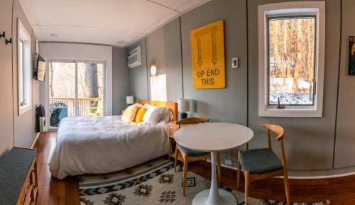 Un dormitorio con una cama y una mesa y sillas. en Modern Tiny House with hot tub & river near Stowe, en Johnson