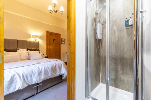 a bedroom with a bed and a shower with a tub at Brooklands 5 Star Guest House in Penrith