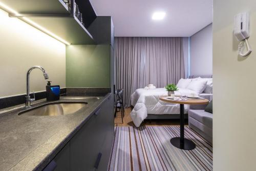 ein Badezimmer mit einem Waschbecken und ein Schlafzimmer mit einem Bett in der Unterkunft Edificio Village Lofts - Ao lado da Vila Germânica in Blumenau