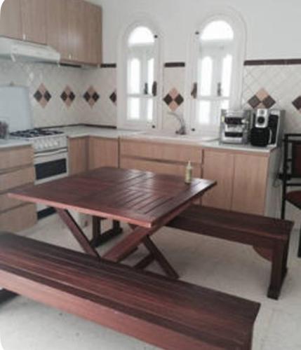 a kitchen with a wooden table and a wooden bench at Aux jardins de Hammamet in Hammamet