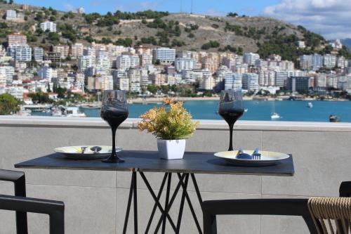 a table with two wine glasses and a view of a city at TopView Apartment In front of Saranda Port in Sarandë