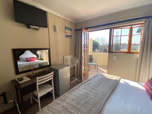 a bedroom with a bed and a desk and a television at Lanseria Country Estate in Lanseria