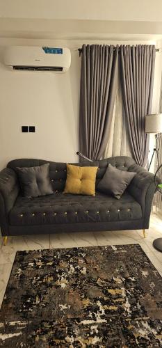 a black couch in a living room with a window at Ladi's place Anthony Ikeja in Lagos