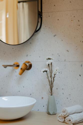 a bathroom with a sink and a vase with flowers at das haus - kisház a völgyben in Tarján