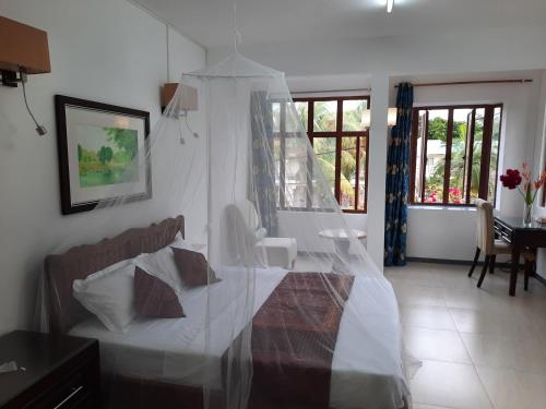 a bedroom with a white bed with a canopy at Jasmin Apartments flic en flac in Flic-en-Flac