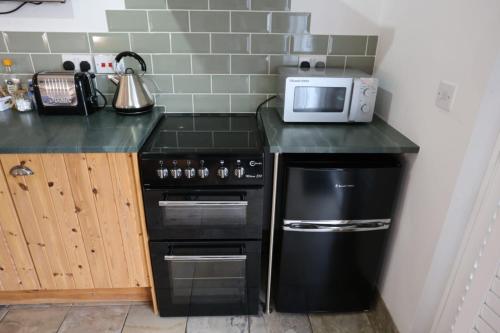 a kitchen with a black stove and a microwave at Lynton Lodge Studios in Keswick