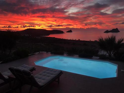 a swimming pool with a sunset in the background at Krinakia Villas in Xerokampos
