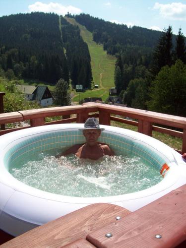a man in a hot tub on a deck at Apartmány a Chalupa Tara in Albrechtice v Jizerských horách