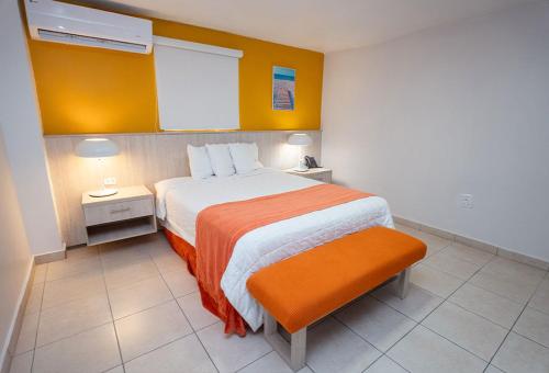 a bedroom with a large bed with an orange blanket at Hotel Vista Bahia & Marina in Salinas