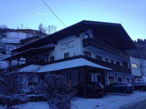 a large white building with cars parked in the snow at Frühstückspension Auer - Haus Kargl in Schladming