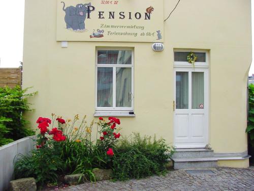 a yellow building with a white door and red flowers at Pension Pieschen Dresden in Dresden