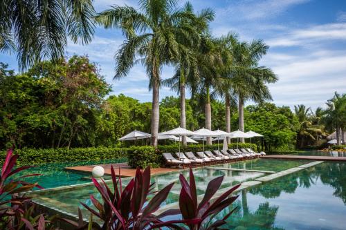 a swimming pool with white umbrellas and palm trees at Grand Velas Riviera Maya - All Inclusive in Playa del Carmen