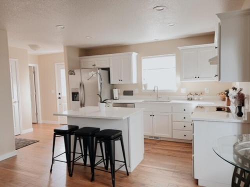 una cocina con armarios blancos y taburetes negros en Centrically Located Hillsboro Home, en Hillsboro