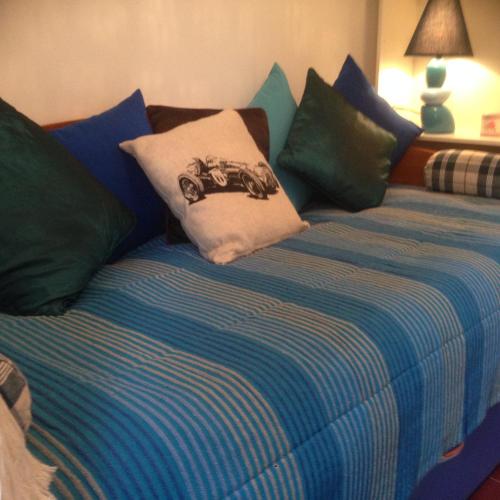 a bed with blue and green pillows on it at Casas do Patio sem Cantigas 1 in Sintra