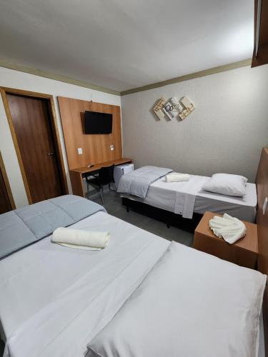 a hotel room with two beds and a television at Hotel Villa Real in Piratininga