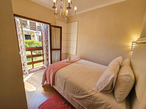 a bedroom with a bed and a large window at Capivari Flat in Campos do Jordão